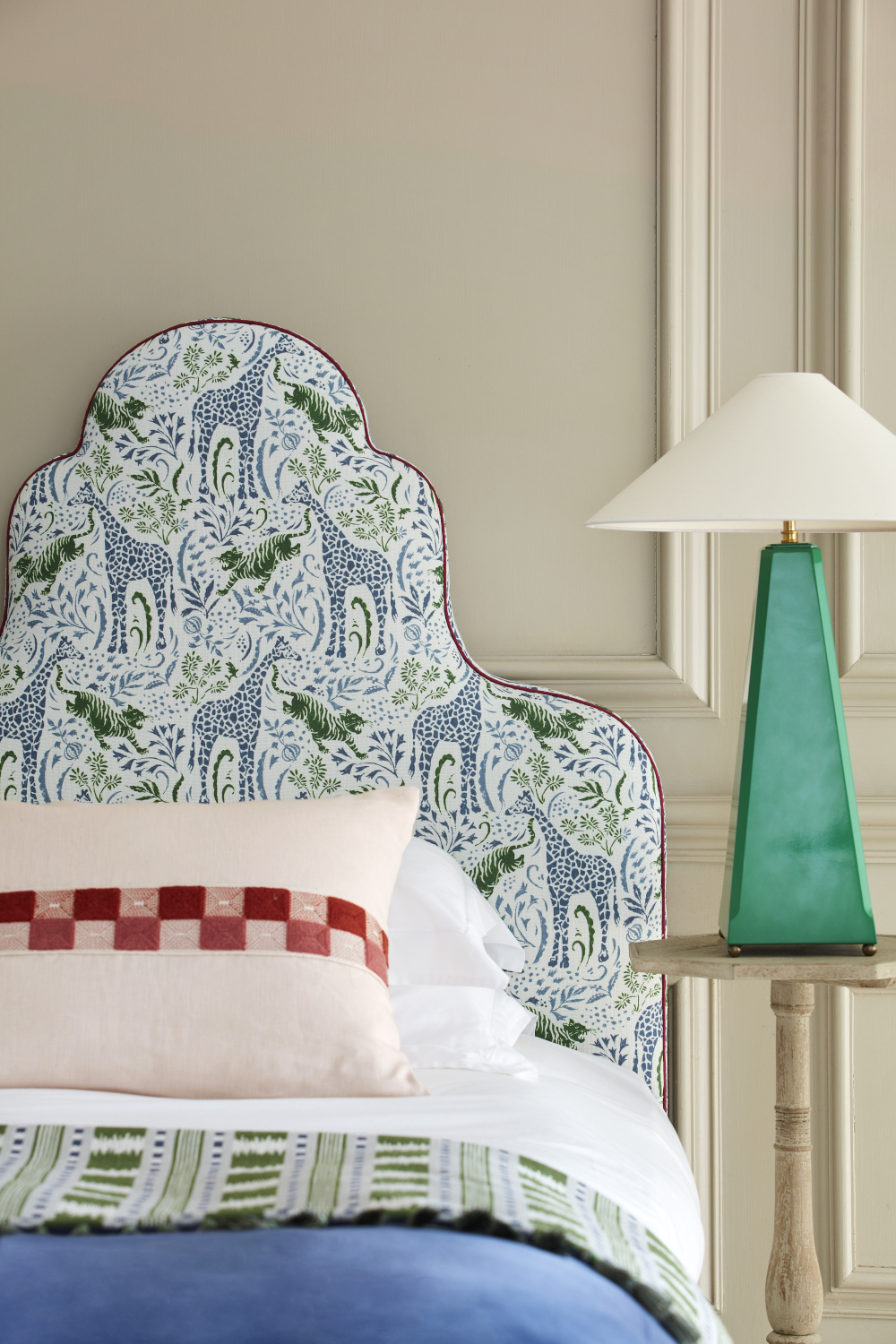 Image of upholstered bed frame with green lamp on bedside table